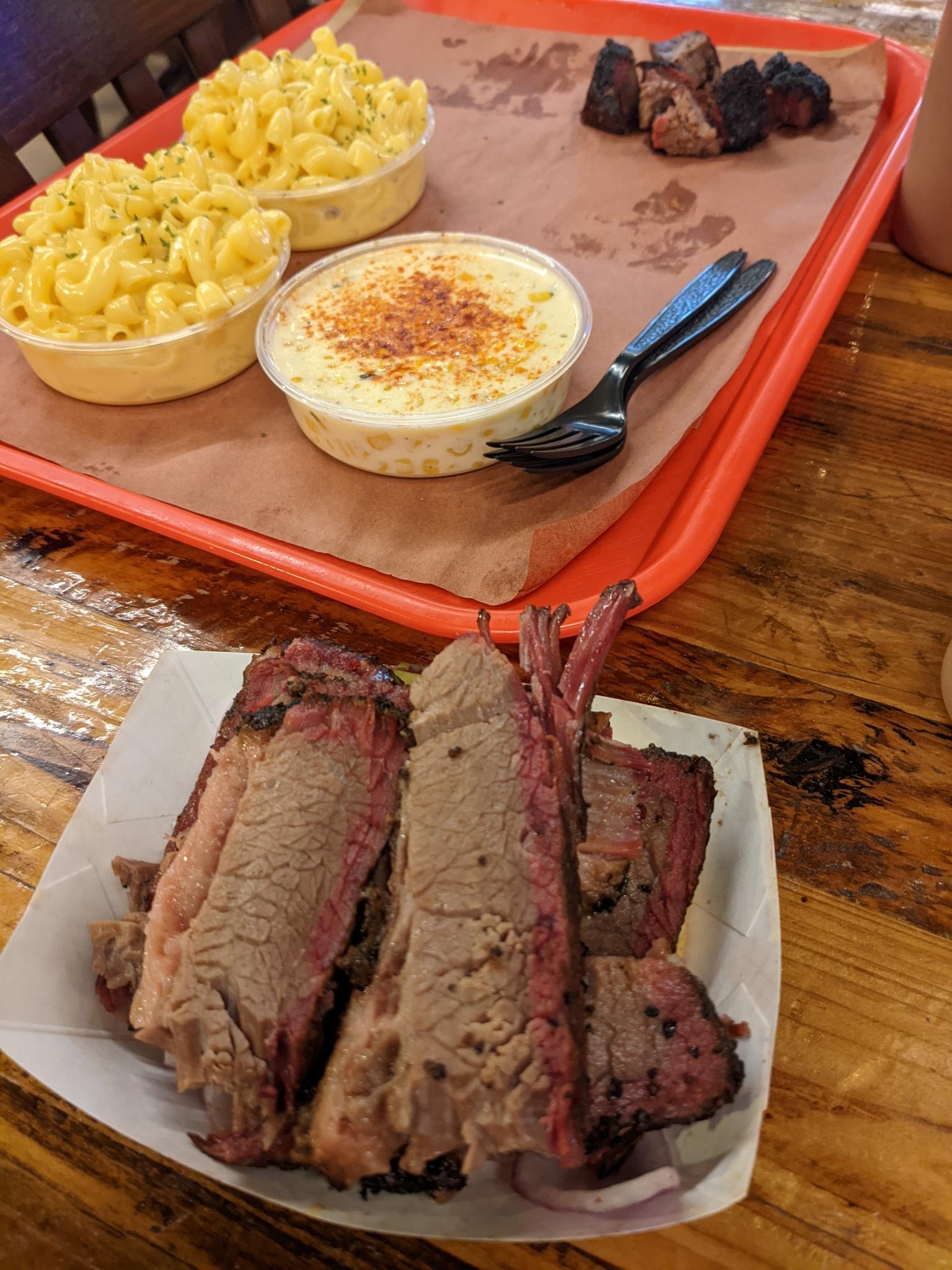 Texas brisket piled onto a sandwich with sides of macaroni and cheese, cream corn, and burnt ends