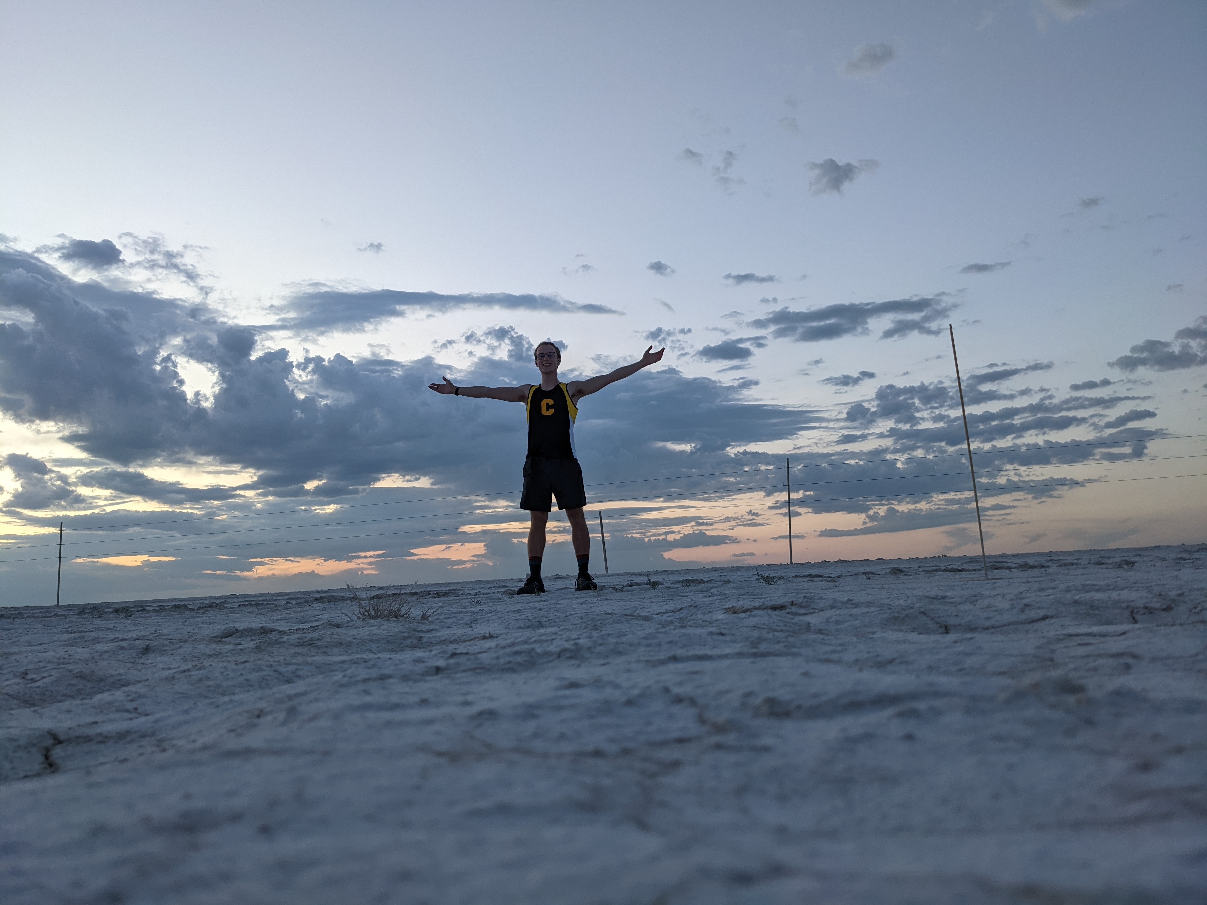 Kyle with arms spread standing on Salt Flats west of the Guadalupe Mountains
